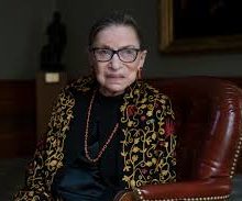 Picture of Ruth Bader Ginsberg seated. She wears a floral cardigan.