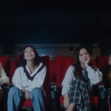 The 4 members of Blackpink sitting in a movie theatre.