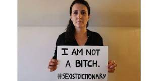 A woman holding a sign saying, "I am not a bitch. Hashtag Sexist Dictionary"