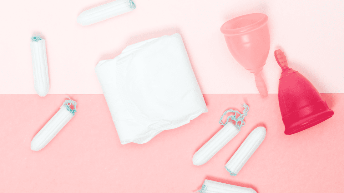 Various period products scattered on a pink backdrop