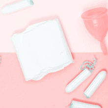 Various period products scattered on a pink backdrop