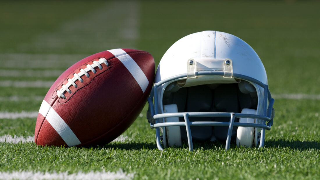 Football and helmet on field