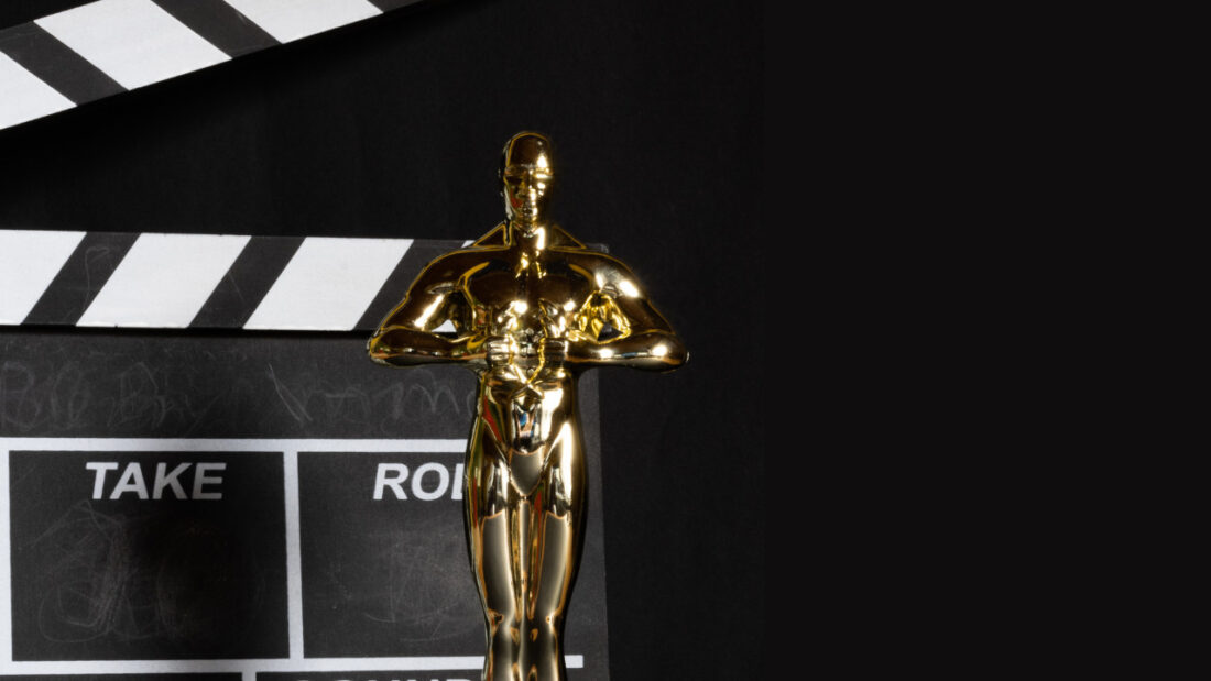 Academy Award statue and movie clapper against black background