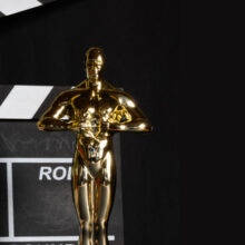 Academy Award statue and movie clapper against black background