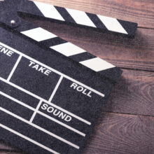 A close-up of a traditional movie clapperboard resting on a wooden surface.