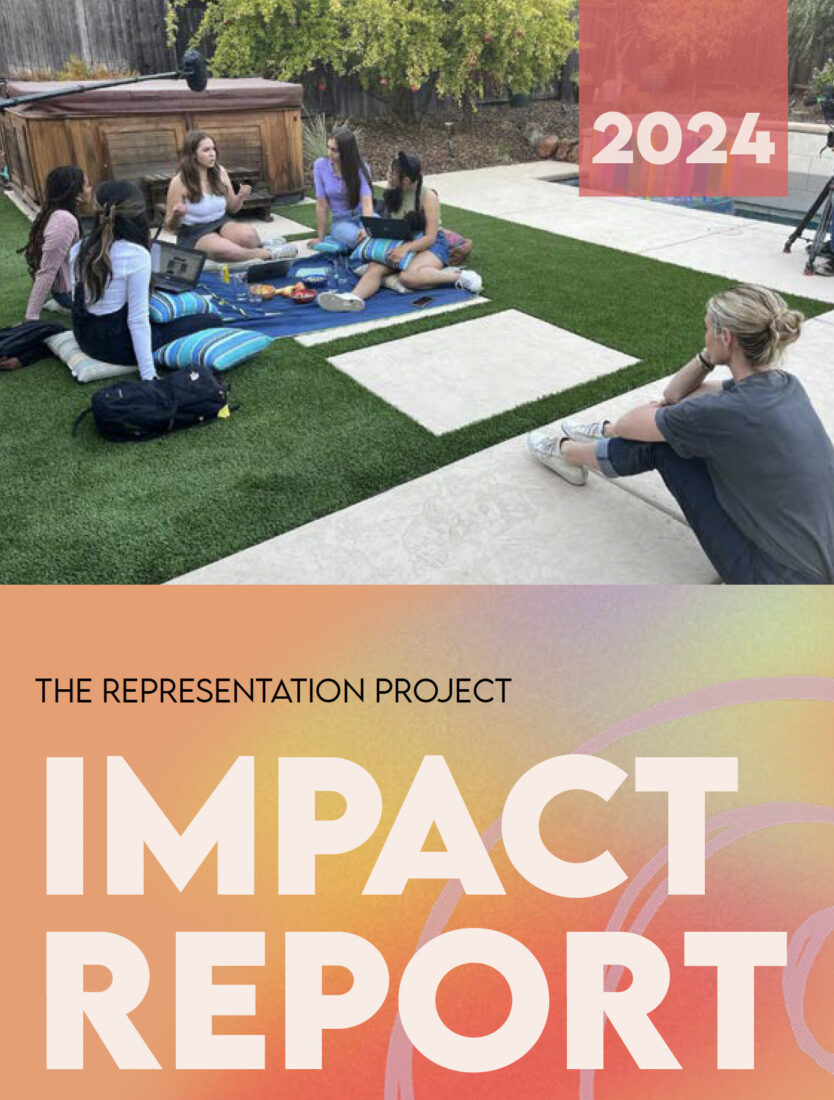 People sitting in a circle on artificial turf in a backyard setting, engaging in conversation. A hot tub and trees are in the background. Overlay text reads "2024" and "The Representation Project Impact Report." Discover more insights at The Representation Project website.